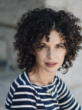 A photo of 艾琳Willer, a woman with dark curly hair 和 a blue 和 white striped shirt